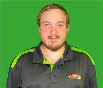 Employee with black shirt and brown hair by a green background 